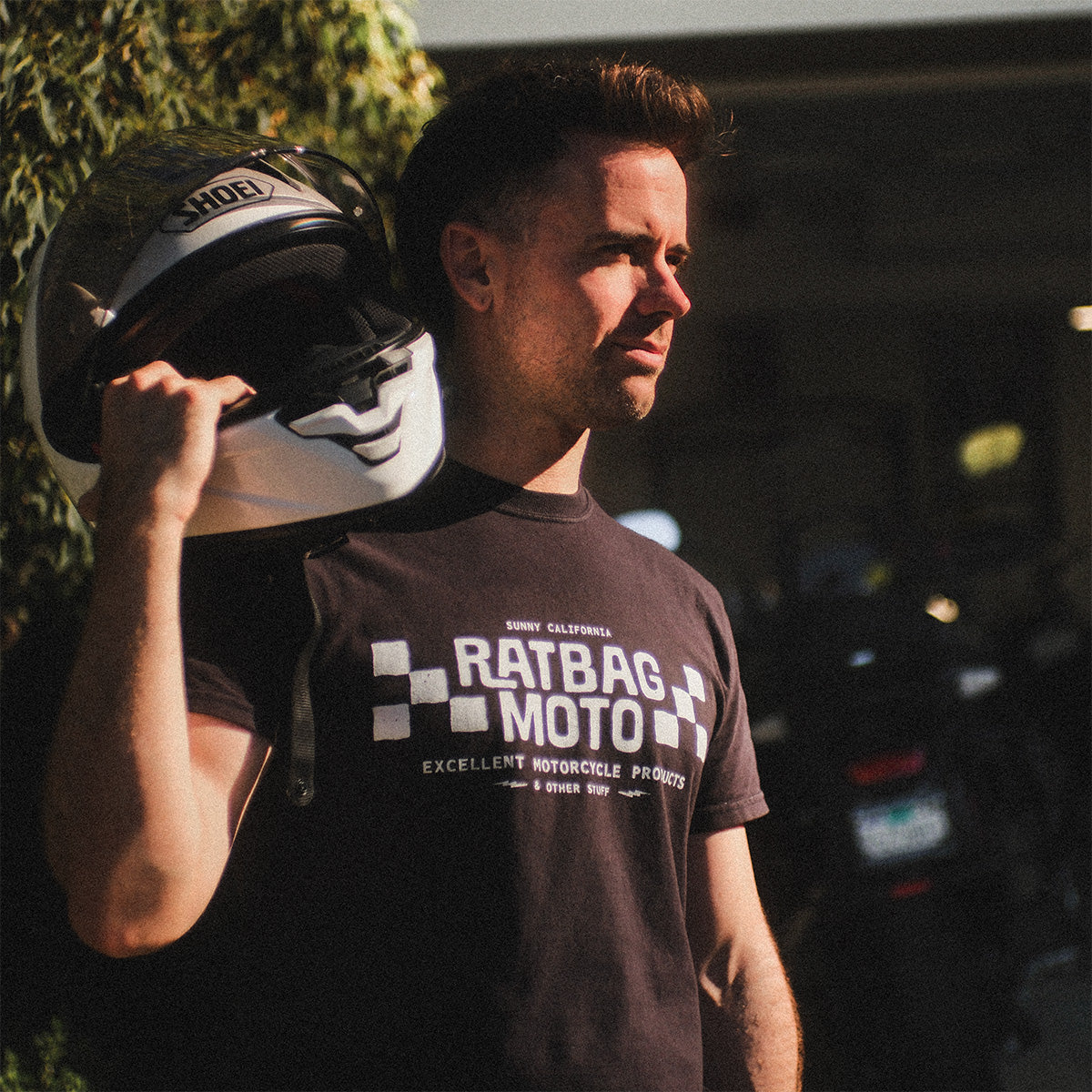 Ratbag Moto lifestyle photo outside an open garage with motorcycles in the background.